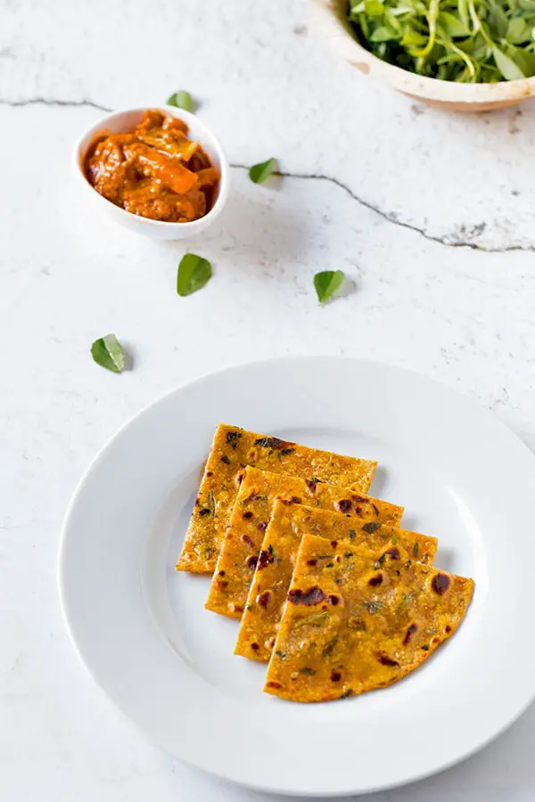 Methi Thepla served in a plate with some mixed pickle as an accompaniment