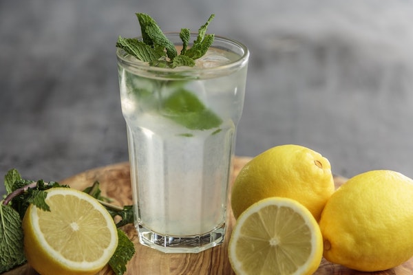 lemonade in a glass surrounded by lemons and mint