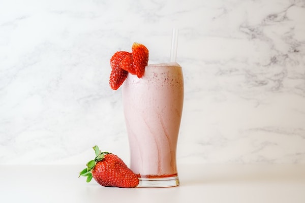 strawberry milkshake in a glass with straw