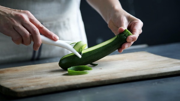 a man peeling zucchini using peeler